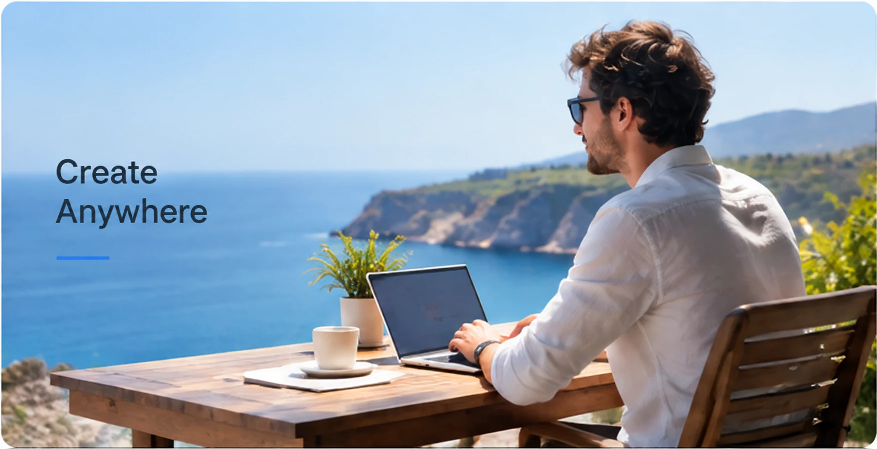 A man working on a laptop on a seaside terrace, with the words Create Anywhere on the left